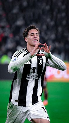 a young man is playing soccer on the field with his hands up in the air