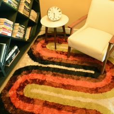 a living room with a chair, book shelf and clock on the floor in front of it