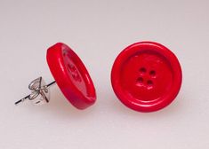 a pair of red buttons sitting on top of a white table next to each other