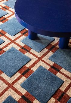 a blue coffee table sitting on top of a carpet covered in red, white and blue squares