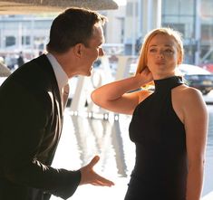 a woman in a black dress standing next to a man