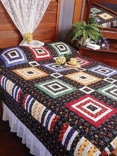 a bed with a quilt on top of it next to a dresser and mirror in a room