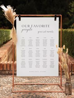 a sign that is sitting on top of a stone floor next to some flowers and grass