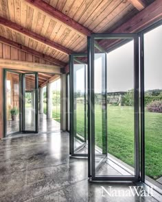 an empty room with glass doors and grass in the backround, looking out onto a large open field