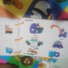 a person holding up a children's book with pictures of cars and trucks on it