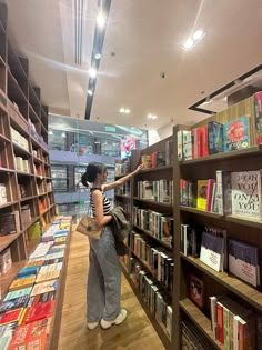 two women looking at books on shelves in a library, one is reaching for the book