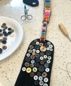 a table topped with lots of different types of buttons next to scissors and pliers