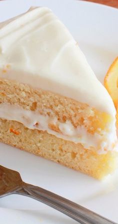 a piece of cake with white frosting and an orange slice next to it on a plate