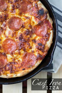 a pepperoni pizza in a cast iron skillet on top of a wooden table