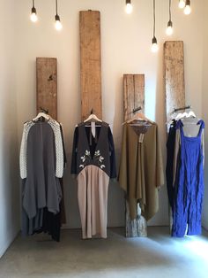 clothes are hanging on the wall in front of two wooden poles with lights above them