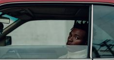 a man sitting in the drivers seat of a red car