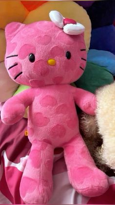 a pink hello kitty stuffed animal sitting next to a brown teddy bear on a bed