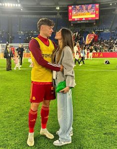 a man and woman standing on top of a soccer field