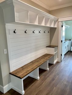 an empty room with white painted walls and wooden benches on the wall, along with several open shelving units