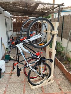 there is a bike that is on top of a wooden stand in the yard with wheels attached to it