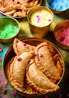 several bowls filled with different colored powders and pastries next to each other on a table