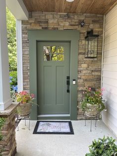 a front door with two planters on either side and a welcome mat in the middle