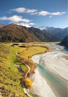 an aerial view of a river running through a valley with mountains in the back ground