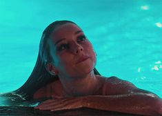 a woman swimming in a pool with her arms crossed and head tilted to the side