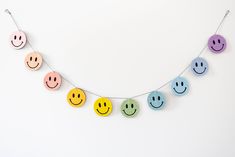 a string of smiley face magnets hanging on a white wall with strings attached to it