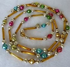 a multicolored beaded necklace on a white surface with gold beads and pearls