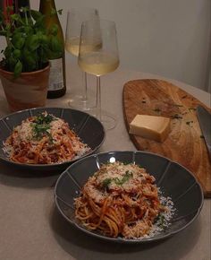 two plates of spaghetti with parmesan cheese and wine