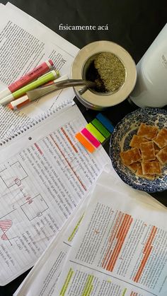 a table topped with papers and bowls filled with food next to a cup of coffee