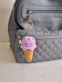 a crocheted ice cream cone keychain hanging from a gray purse strap