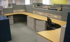 an office cubicle with two desks and several file cabinets