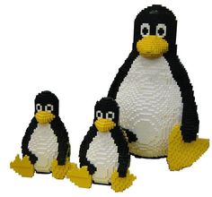 three lego penguins sitting next to each other on a white surface with one penguin standing between two smaller penguins