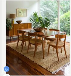 a dining room table with chairs and a potted plant in the middle on a rug