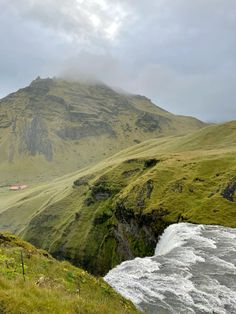 the mountains are covered in green grass and water