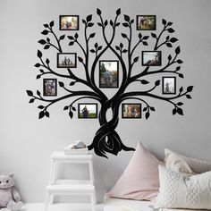 a family tree with many pictures hanging on it's wall and a teddy bear sitting next to it