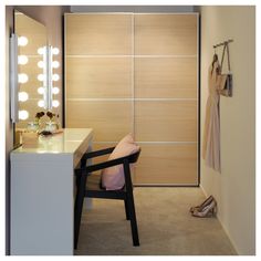 a chair sitting in front of a mirror next to a dressing room with lights on