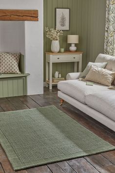 a living room with green walls and wood flooring on the floor, white couches and coffee table