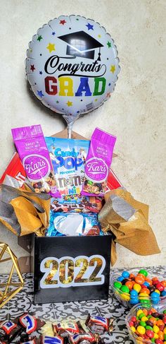 a table topped with candy and balloons next to a sign that says congratulations grad