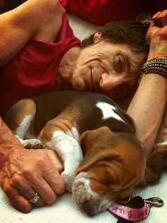 a woman laying on top of a bed next to a brown and white dog