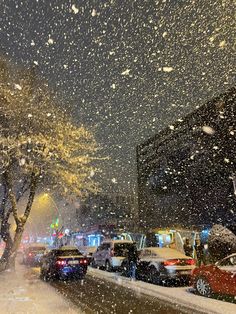 cars are parked on the side of the road as it is snowing at night