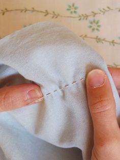 someone is stitching something on the fabric with their thumbnails, and they are holding it close together