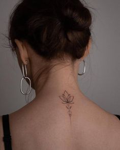 a woman's back neck with a small flower tattoo on her left side ribcage