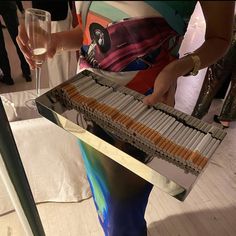 a woman is holding a tray full of cigars and wine glasses in her hand