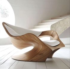 an unusual wooden chair sitting on top of a hard wood floor next to some stairs