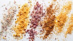 four different types of spices on a white surface with one red, the other yellow