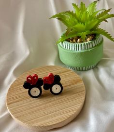 a pair of mickey mouse ear studs sitting on top of a wooden tray next to a potted plant