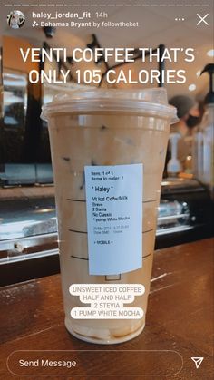 a cup of coffee sitting on top of a wooden table next to a menu board