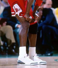 a basketball player with his foot on the court and holding his leg up to his knee