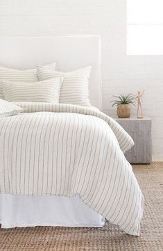 a bed with white and grey striped linens