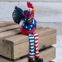 a rooster figurine sitting on top of a wooden pallet with an american flag scarf