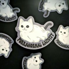 several stickers with cats on them are shown in the dark, one is white and the other has black lettering