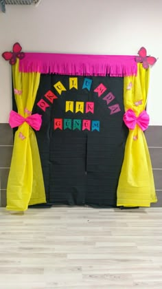 a black and yellow birthday backdrop with pink ribbon on the top is decorated with butterflies